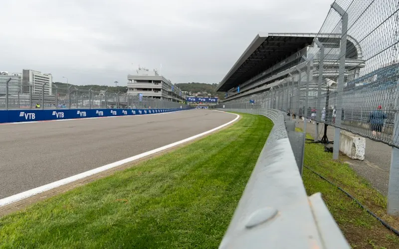 Empty racing circuit curving through grass with grandstands nearby