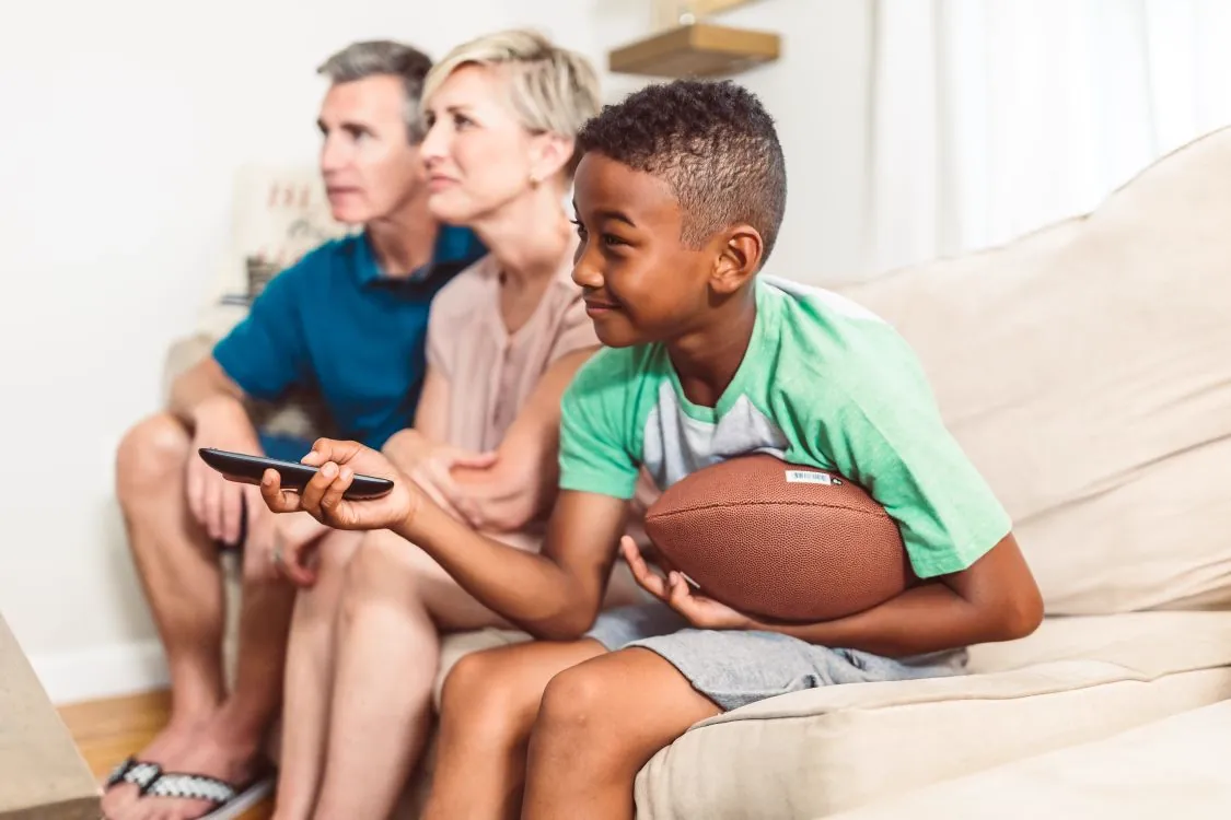 Family watching television together in a cozy living room, highlighting the importance of IPTV parental controls for child safety at home