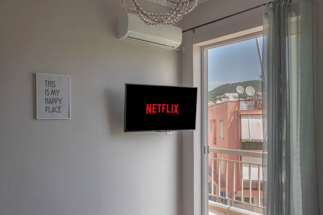 Wall-mounted television turned on displaying a streaming interface, representing IPTV apps available on Apple TV tvOS platform