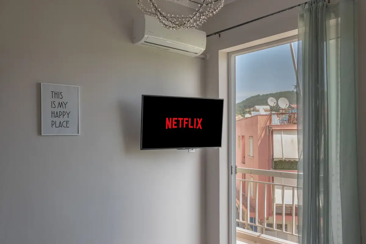 Wall-mounted television displaying a streaming service interface in a modern living room with natural light, illustrating the IPTV Smarters Pro polished viewing experience on Apple TV