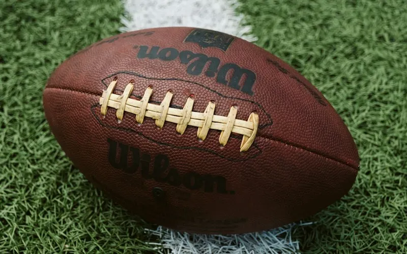 American football resting on green grass